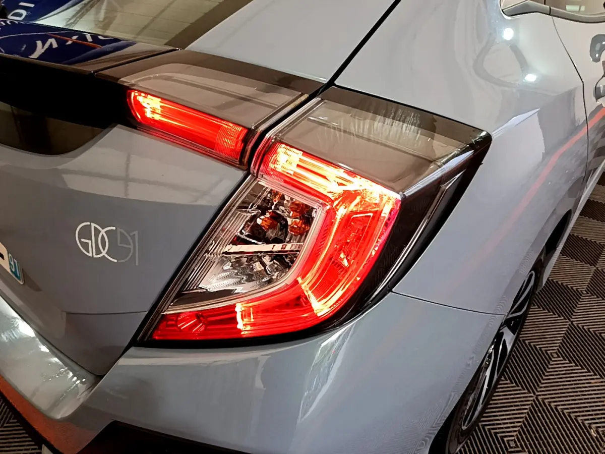 Gros plan sur le feu arrière droit rouge d'une Honda Civic gris foncé 2020, avec partie de la carrosserie visible.