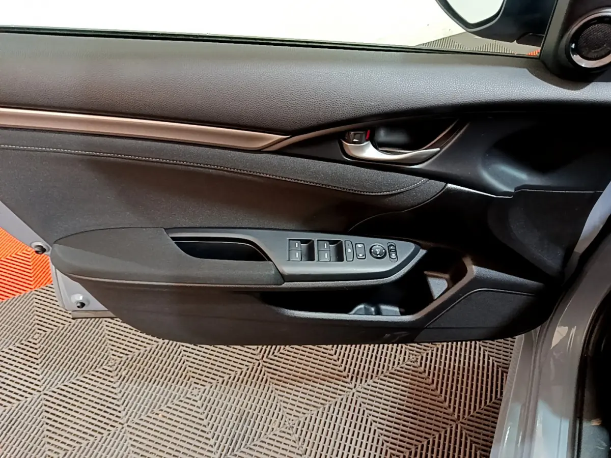 Vue rapprochée de la porte avant gauche grise de la Honda Civic 1.0 i-VTEC avec commandes électriques des vitres et rétroviseurs.
