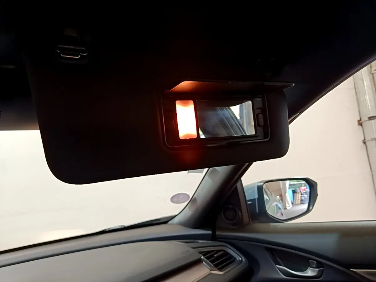 Vue intérieure côté conducteur de la Honda Civic gris foncé 2020, avec pare-soleil et miroir éclairé visible.