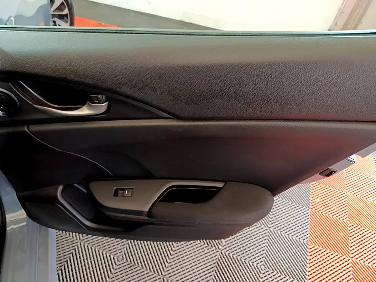 Gros plan sur la porte côté gauche de la Honda Civic 1.0 i-VTEC Exclusive gris foncé avec poignée intérieure noire.