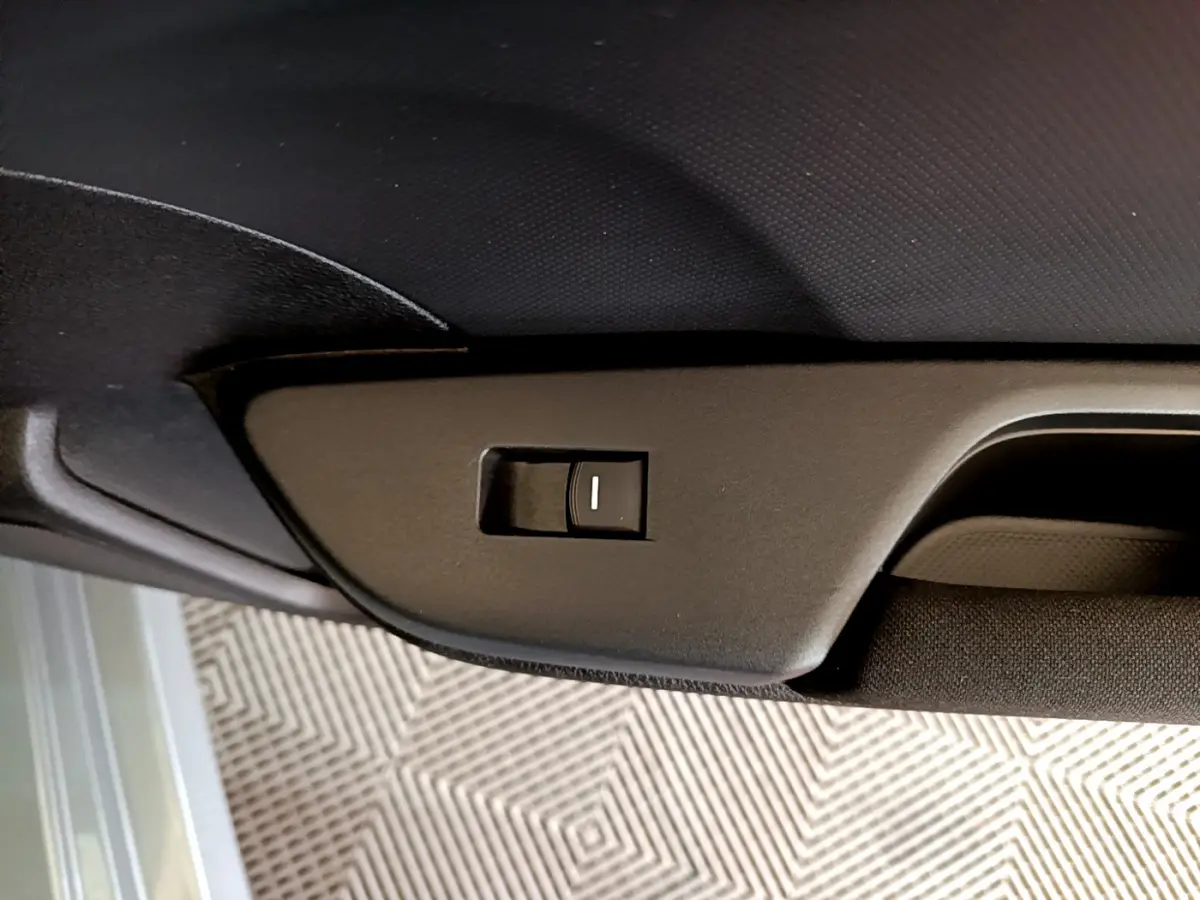Détail du bouton d'ouverture du toit ouvrant sur la garniture intérieure noire d'une Honda Civic gris foncé.