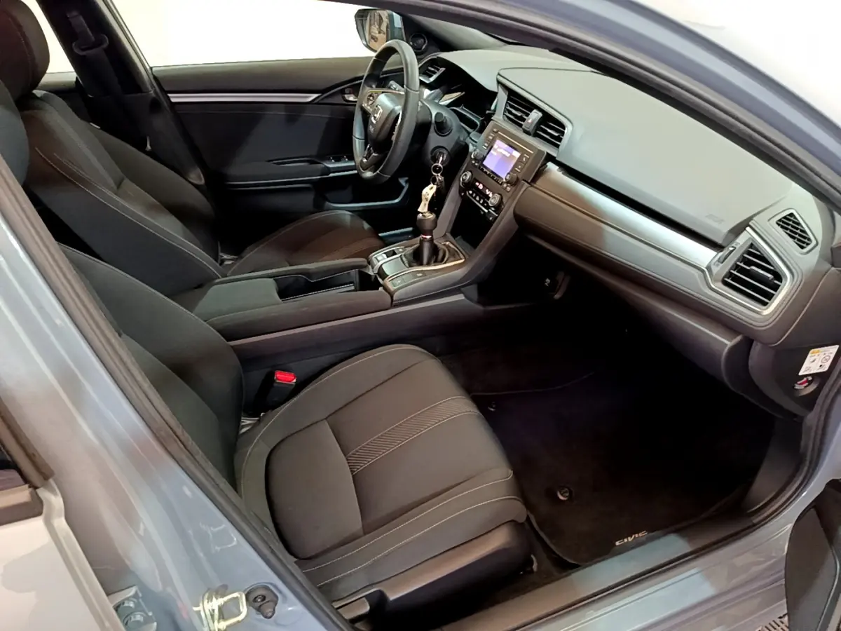 Intérieur avant droit de la Honda Civic 1.0 i-VTEC Exclusive 2020, sièges noirs et tableau de bord moderne.