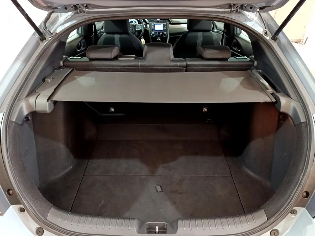 Vue arrière du coffre ouvert d'une Honda Civic gris foncé 2020, avec tablette cache-bagages et sièges arrière visibles.