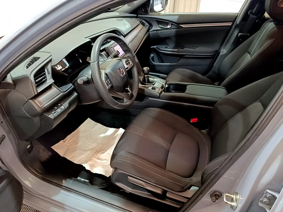 Vue intérieure côté conducteur de la Honda Civic 1.0 i-VTEC Exclusive 2020 avec sièges noirs et tableau de bord moderne.