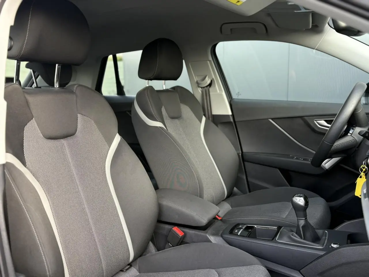 Vue intérieure côté droit montrant les sièges avant gris et la boîte manuelle de l'Audi Q2 30 TDI S-Line 2025.