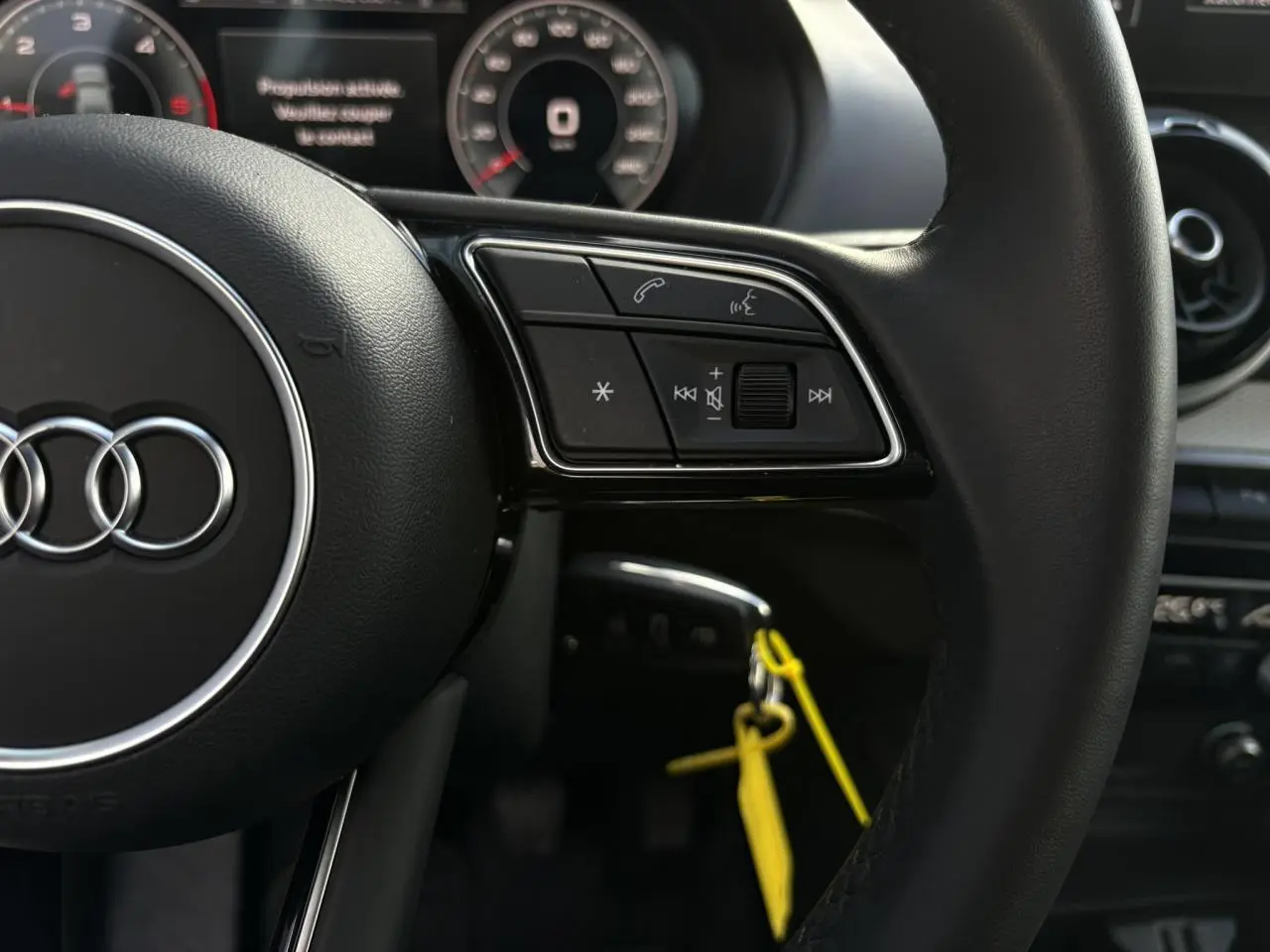 Gros plan sur le volant cuir multifonction de l'Audi Q2 30 TDI S-Line avec commandes audio et téléphone intégrées.