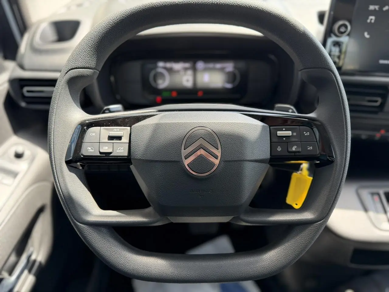 Gros plan sur le volant multifonction noir du Citroën Berlingo ë-136 2025 avec commandes intégrées et logo central rosé.