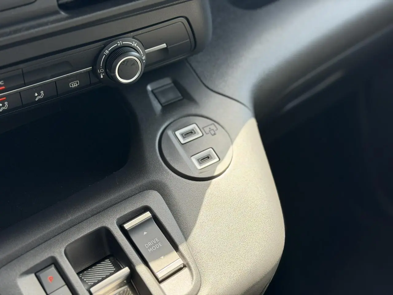 Gros plan sur la console centrale grise du Citroën Berlingo ë-136, montrant le bouton Drive Mode et ports USB.