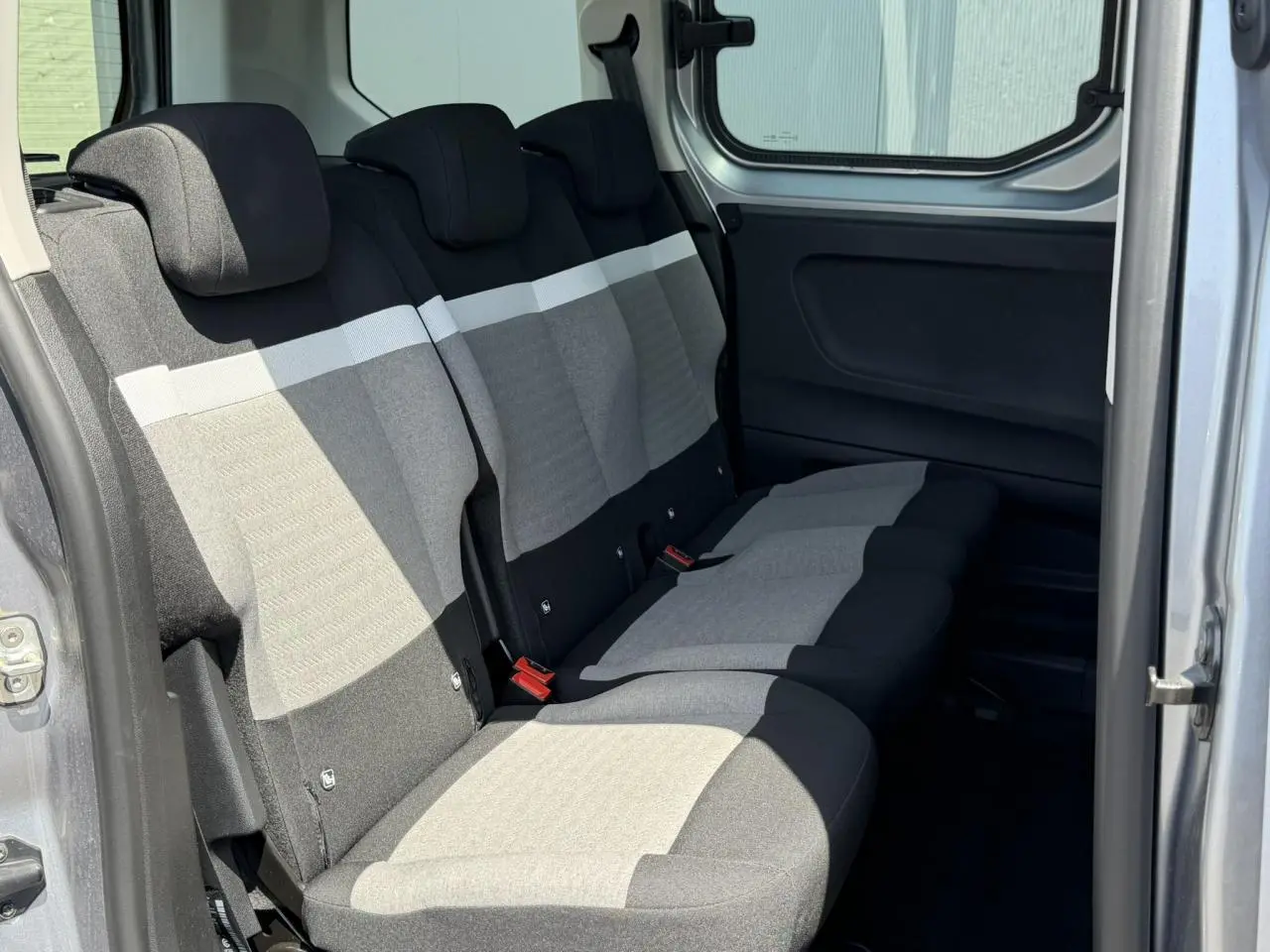 Vue intérieure côté droit sur la banquette arrière gris clair et foncé du Citroën Berlingo ë-136 2025 avec porte coulissante ouverte.