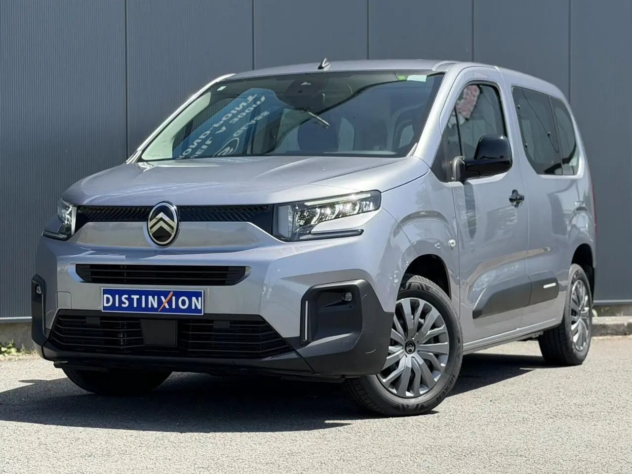 Vue 3/4 avant droit du Citroën Berlingo ë-136 gris Artense avec calandre noire et jantes tôles 16 pouces.
