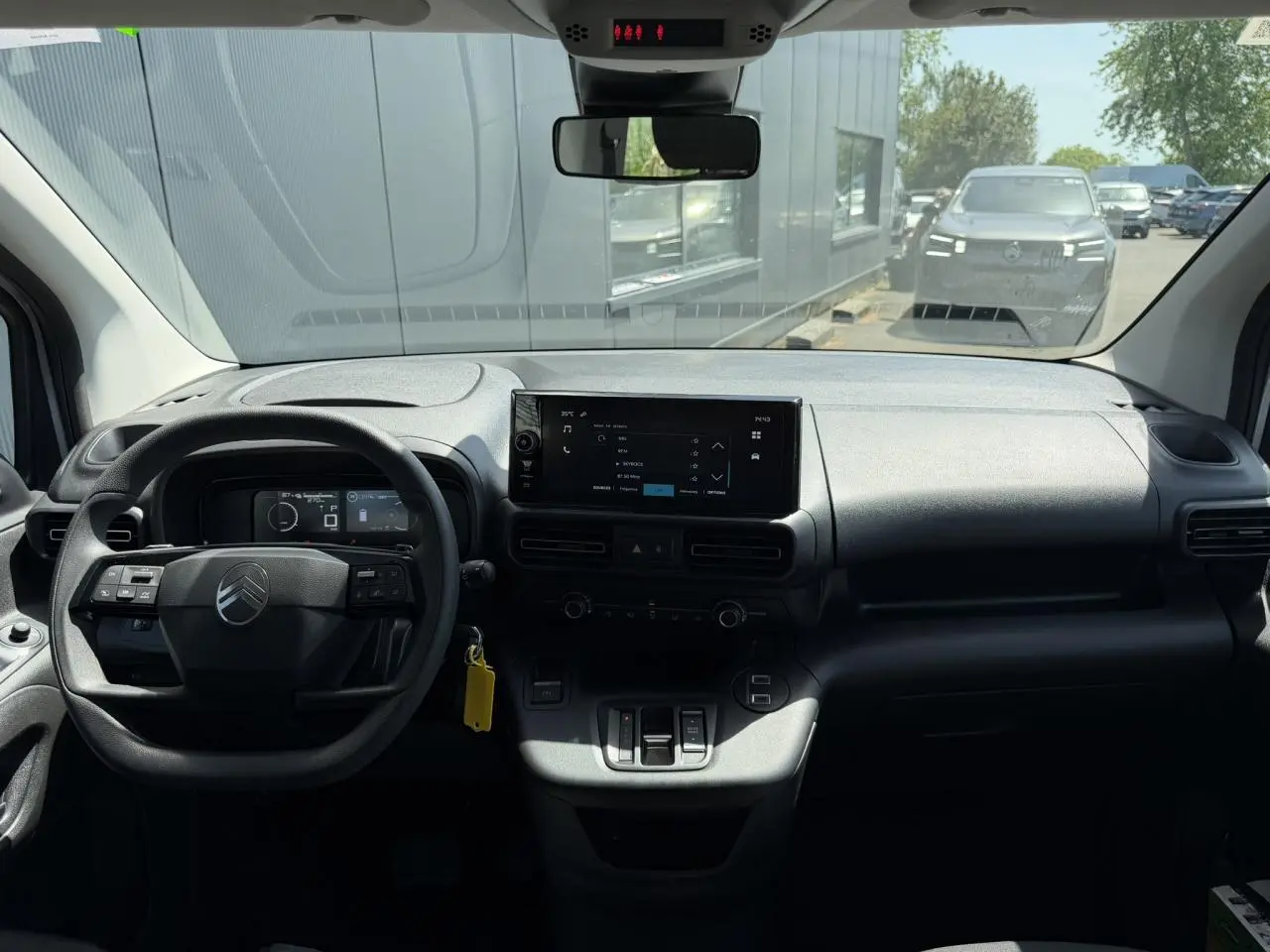 Vue intérieure avant du Citroën Berlingo ë-136 gris Artense, avec tableau de bord et écran tactile central.