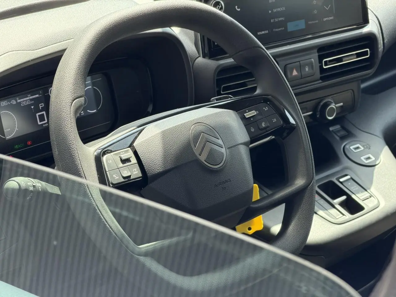 Vue rapprochée du volant multifonction et du tableau de bord numérique du Citroën Berlingo ë-136 gris Artense.