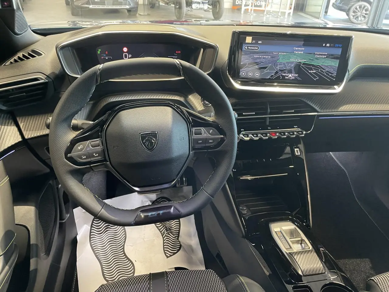 Vue intérieure centrée sur le volant GT et l’écran tactile 10 pouces du Peugeot 2008 hybride 2026, ambiance noire.