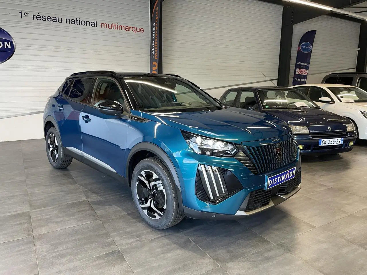 Peugeot 2008 hybride bleu en 3/4 avant droit, avec calandre noire et jantes bicolores distinctives.
