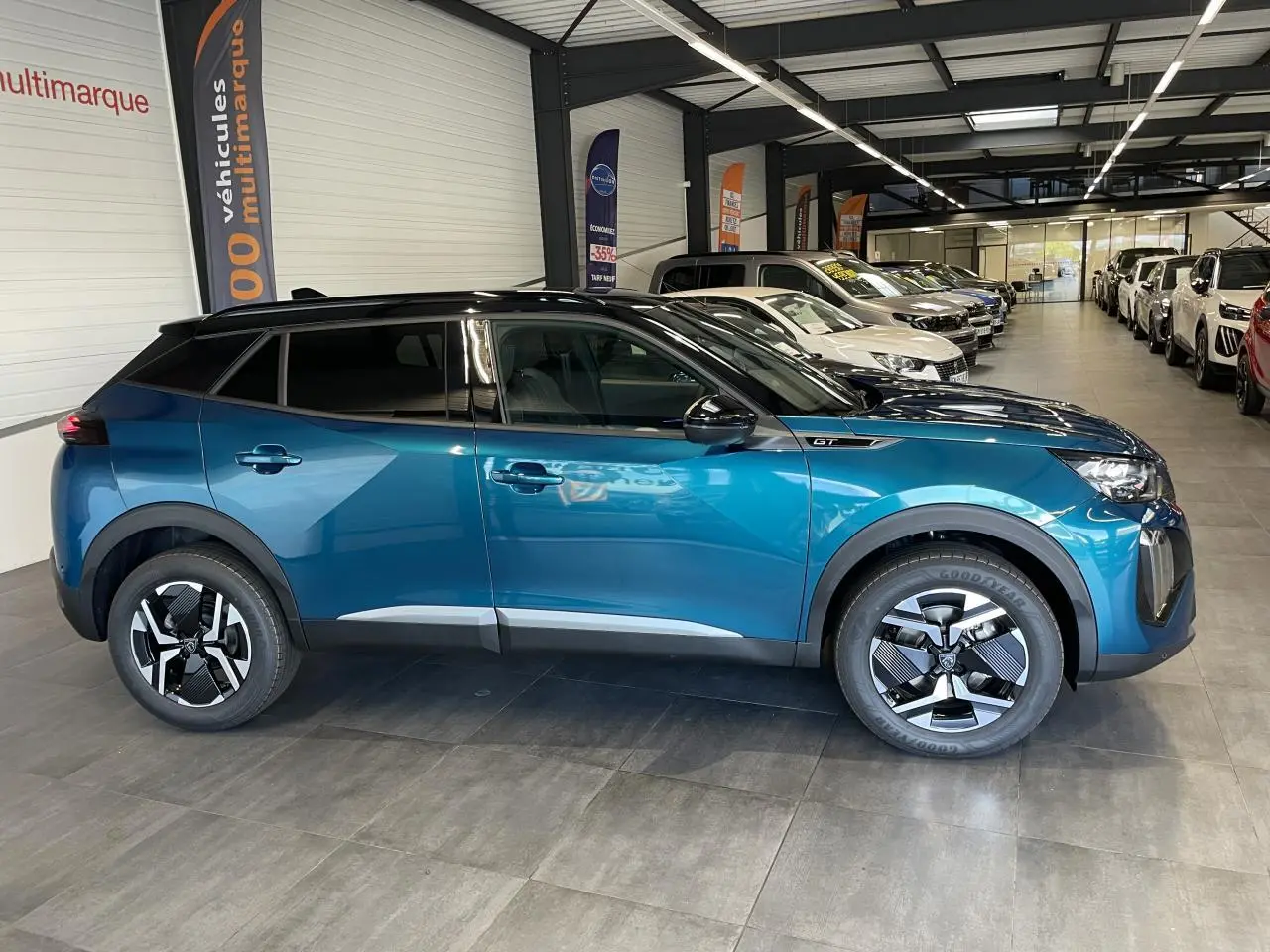 Peugeot 2008 hybride bleu en profil côté gauche, avec toit noir et jantes distinctives en concession.