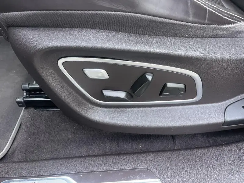 Gros plan sur les commandes électriques de réglage du siège en cuir noir du Renault Espace Gris Cassiopée 2018.