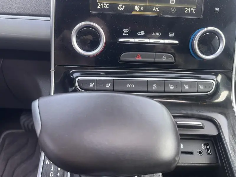 Gros plan sur la console centrale noire du Renault Espace gris Cassiopée, avec commandes climatisation et levier de vitesse automatique.