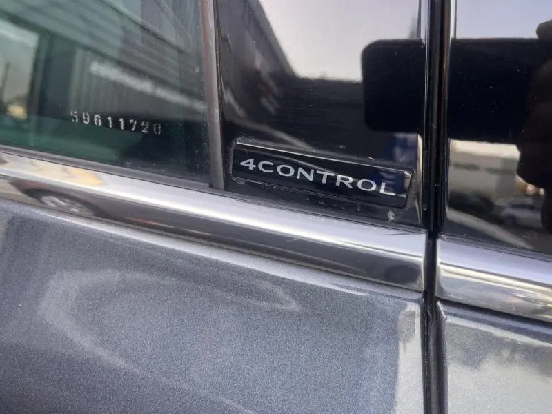 Gros plan sur l’inscription 4CONTROL sur la porte côté gauche d’un Renault Espace gris Cassiopée.