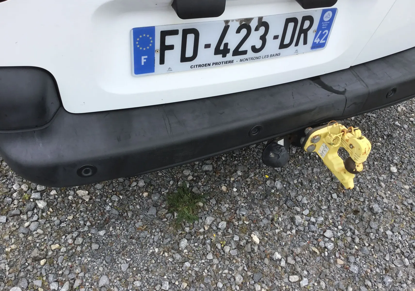 Vue rapprochée de l'arrière blanc d'un Citroën Berlingo 2019 avec attelage jaune et pare-chocs noir.