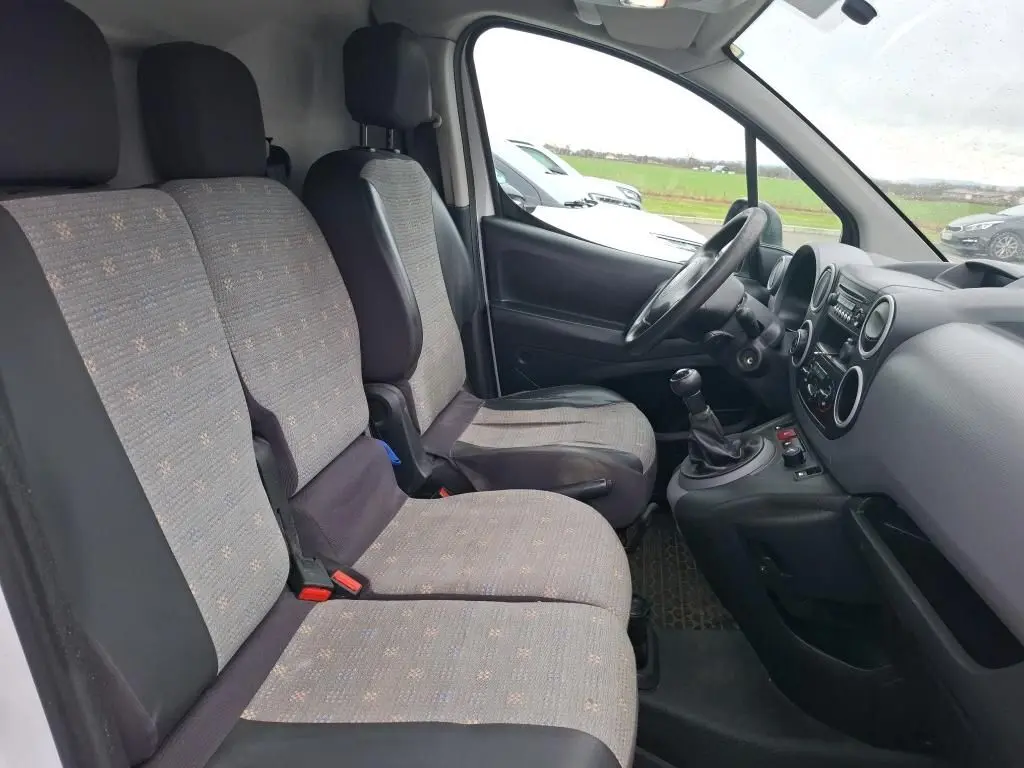 Vue intérieure côté conducteur du Citroën Berlingo blanc 2019, montrant les sièges tissu gris et la console avec boîte manuelle.
