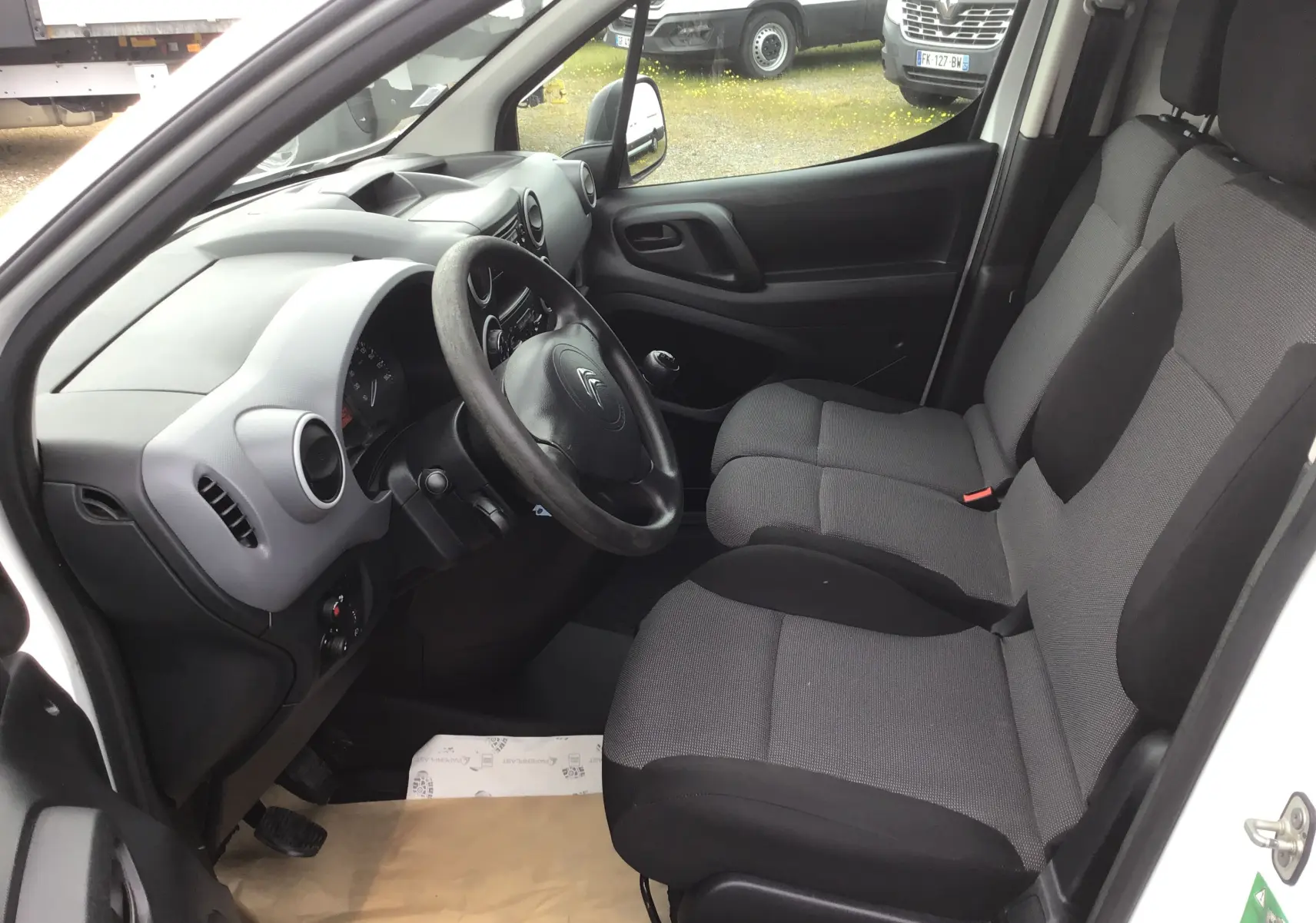 Vue intérieure côté conducteur du Citroën Berlingo blanc 2019, montrant les sièges avant et le tableau de bord simple.