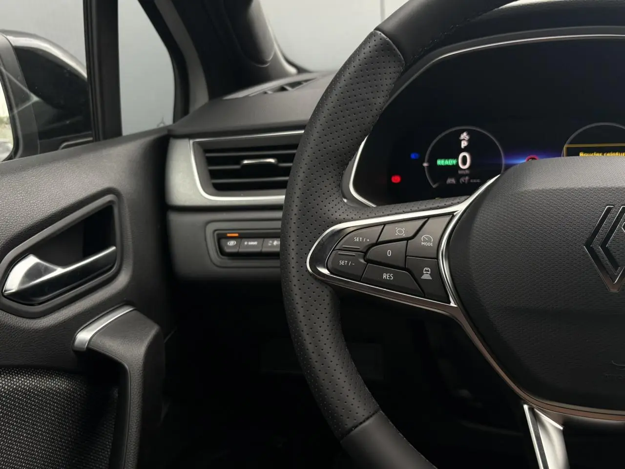 Gros plan sur le volant noir perforé et le tableau de bord numérique du Renault Captur, côté gauche intérieur.