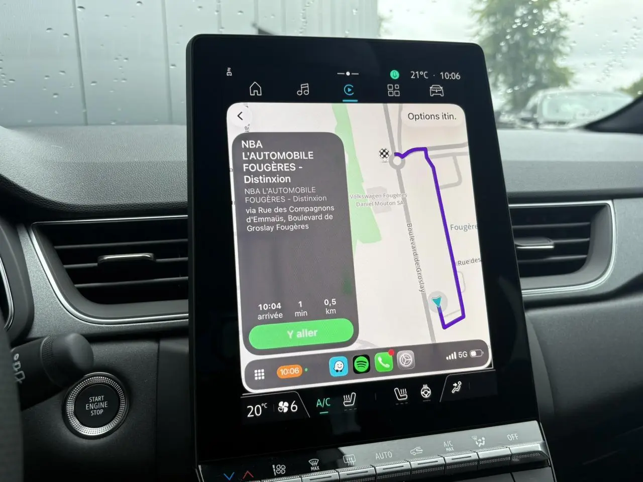 Écran tactile central du Renault Captur blanc nacré, vue intérieure montrant la navigation GPS et commandes climatisation.