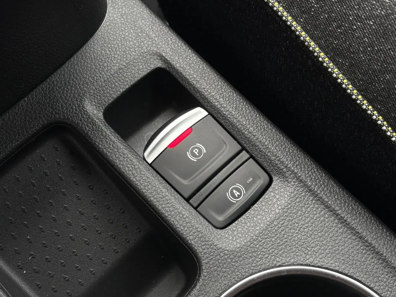Gros plan sur les commandes du frein de parking électrique et auto-hold dans la console centrale noire du Renault Captur.