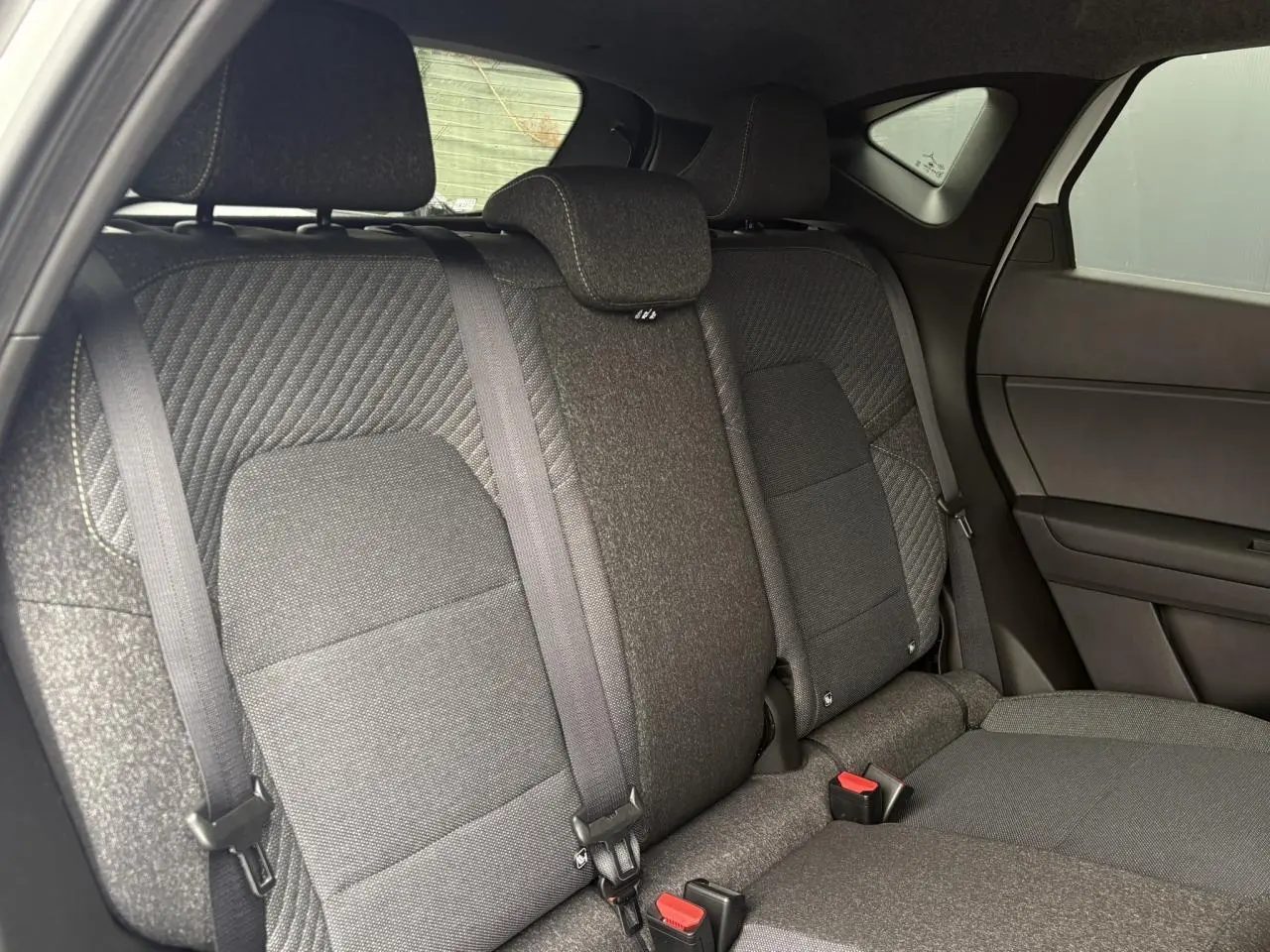 Vue intérieure des sièges arrière en tissu gris foncé du Renault Captur 2026, côté droit, avec ceintures de sécurité visibles.