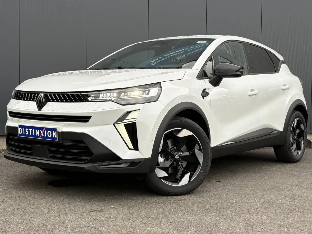 Renault Captur blanc nacré en 3/4 avant droit, avec jantes noires 18 pouces et rétroviseurs noirs brillants.