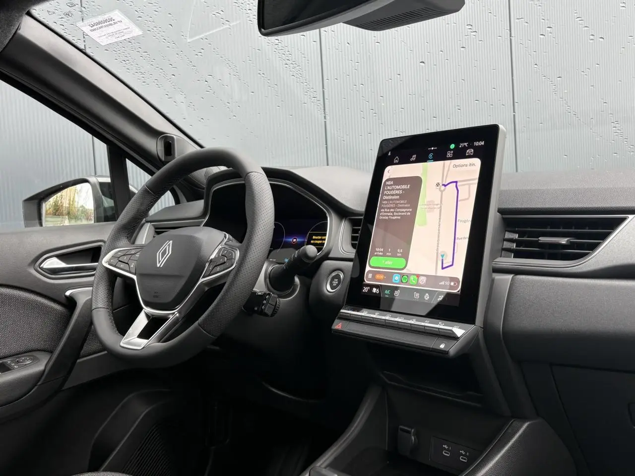 Vue intérieure côté conducteur du Renault Captur blanc nacré 2026, avec grand écran tactile vertical et volant multifonction.