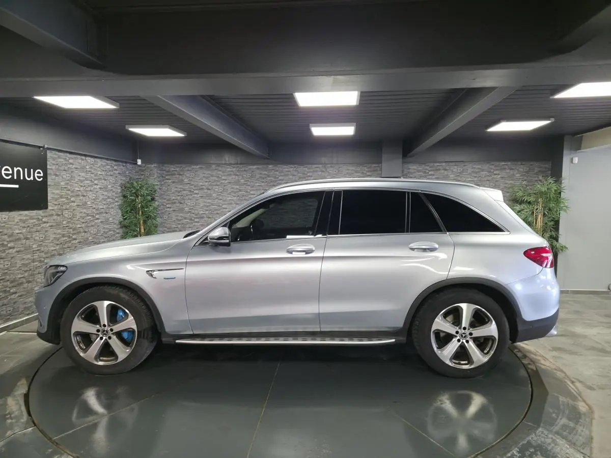 Vue de profil côté gauche d'un Mercedes GLC 350 e gris métallisé avec jantes alliage 19 pouces et marchepieds en acier.