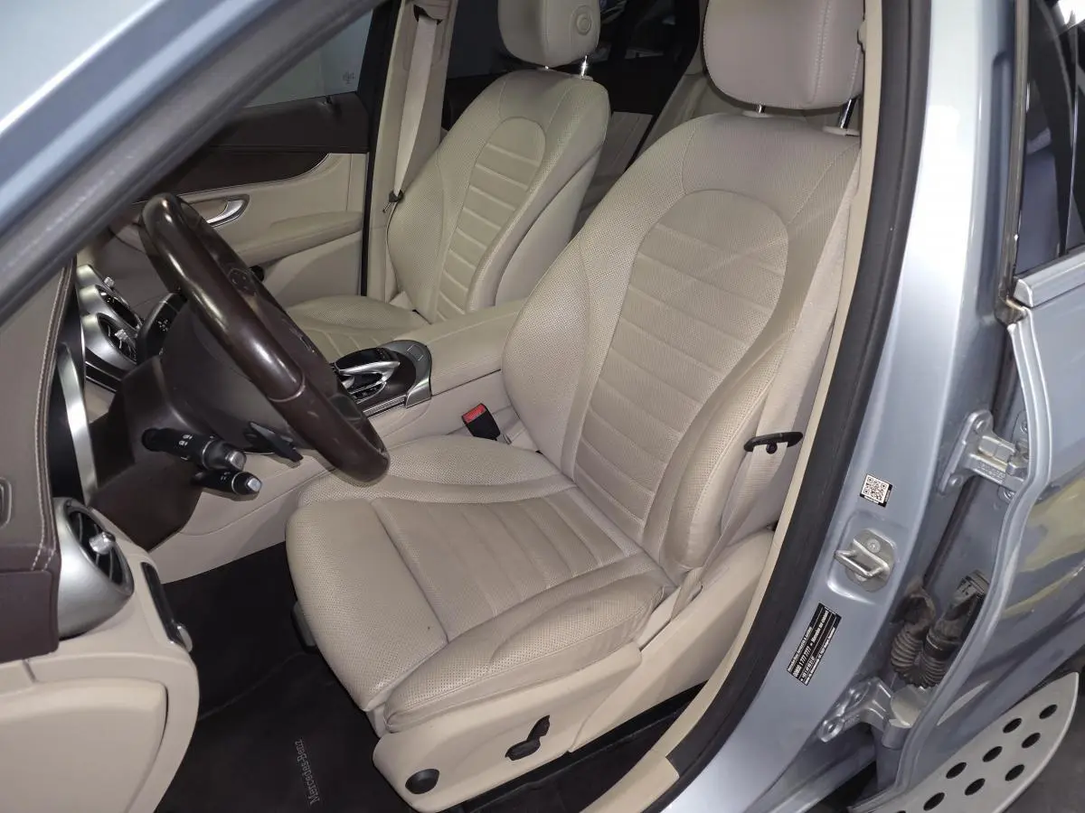 Vue intérieure côté conducteur du Mercedes GLC 350 e gris, sièges cuir beige et tableau de bord marron.