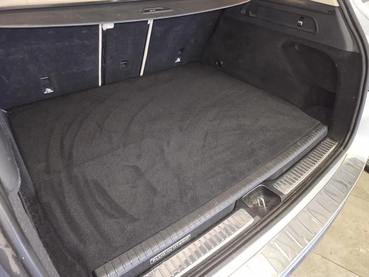 Coffre ouvert vu de dessus d’un Mercedes GLC 350 e gris, avec tapis noir et seuil de chargement inox.