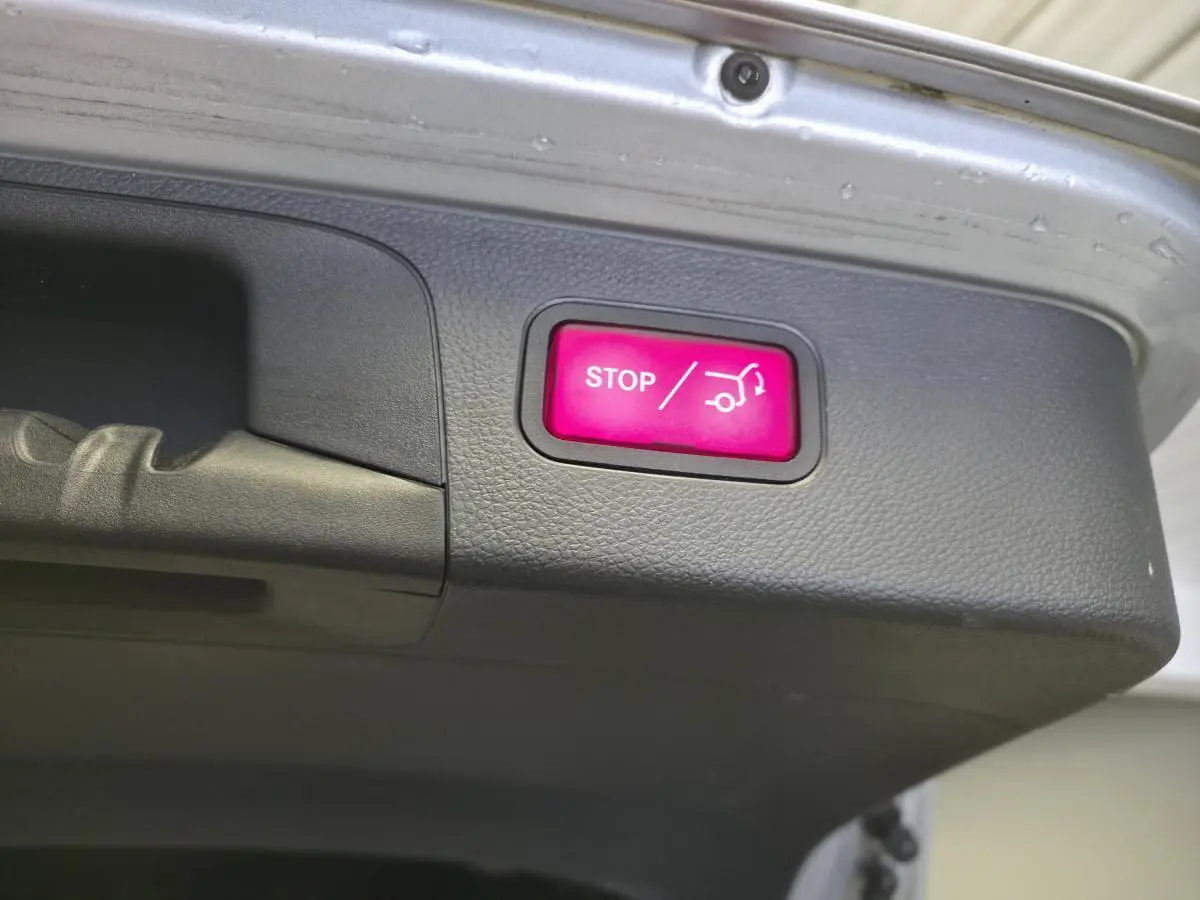 Bouton rouge STOP pour fermeture automatique du hayon sur le coffre d'un Mercedes GLC gris hybride rechargeable.