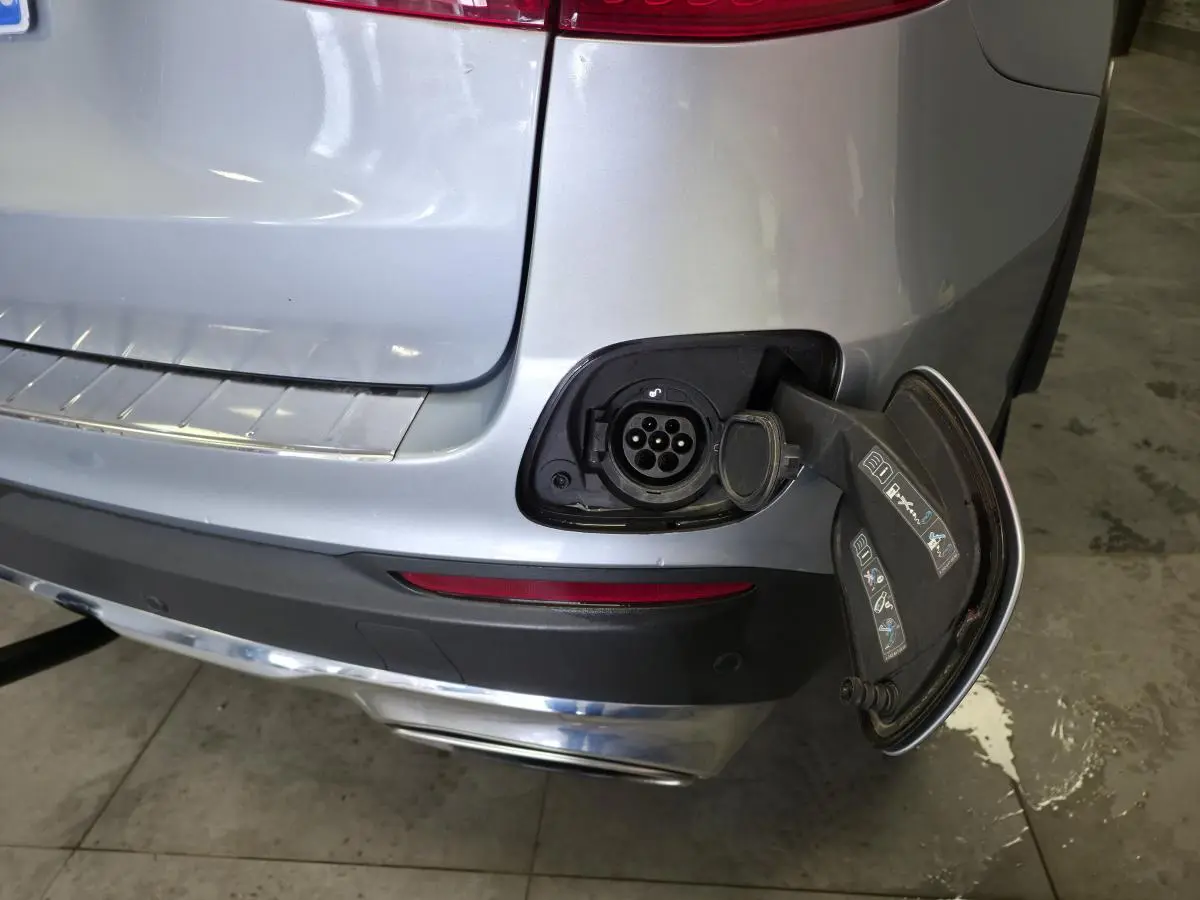 Détail de la prise de recharge ouverte à l'arrière droit du Mercedes GLC 350 e gris métallisé hybride rechargeable.