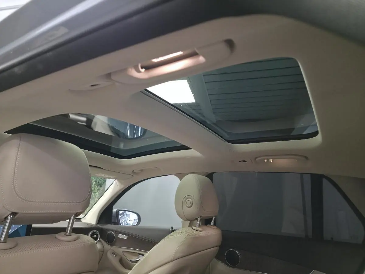 Vue intérieure du toit ouvrant panoramique et des sièges avant en cuir beige du Mercedes GLC 350 e gris de 2017.