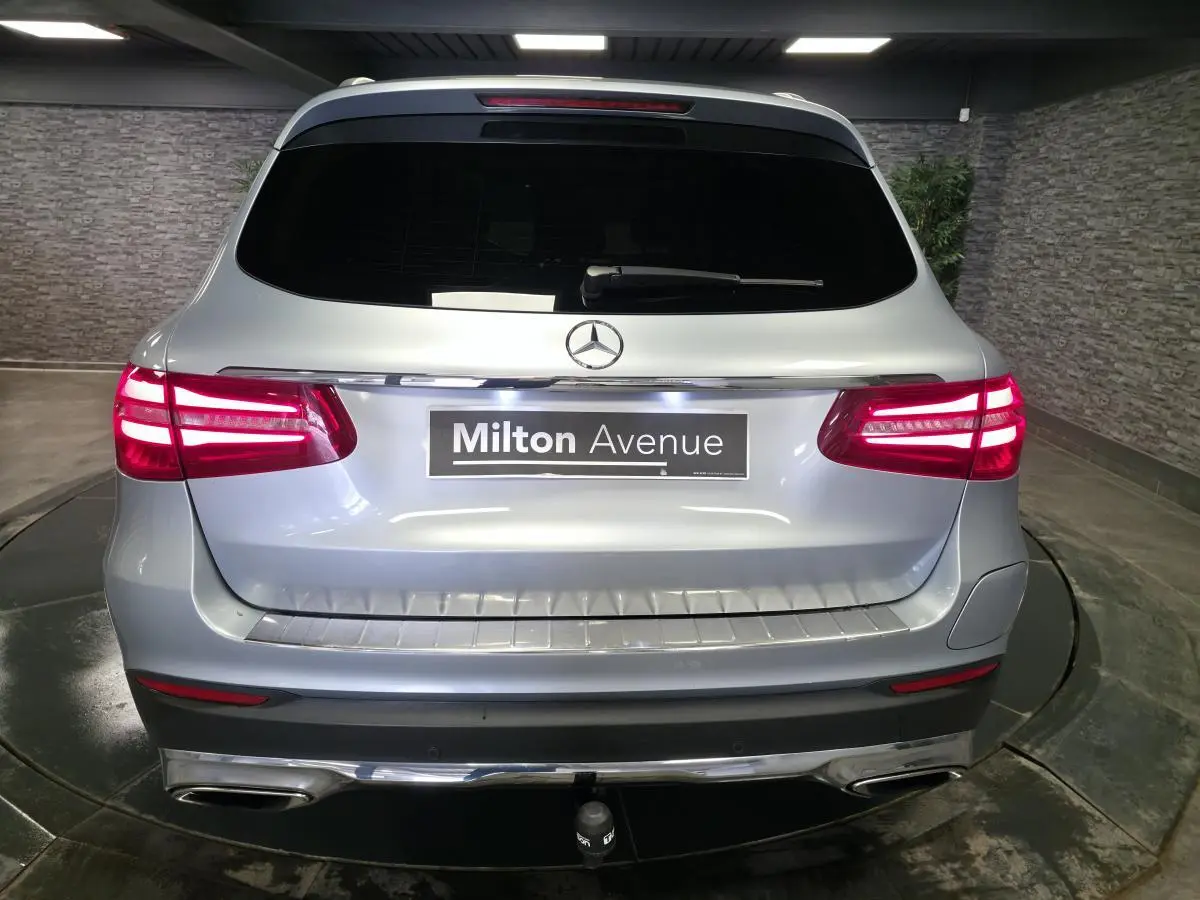 Vue arrière d'un Mercedes GLC 350 e gris métallisé avec feux LED allumés et attelage visible.