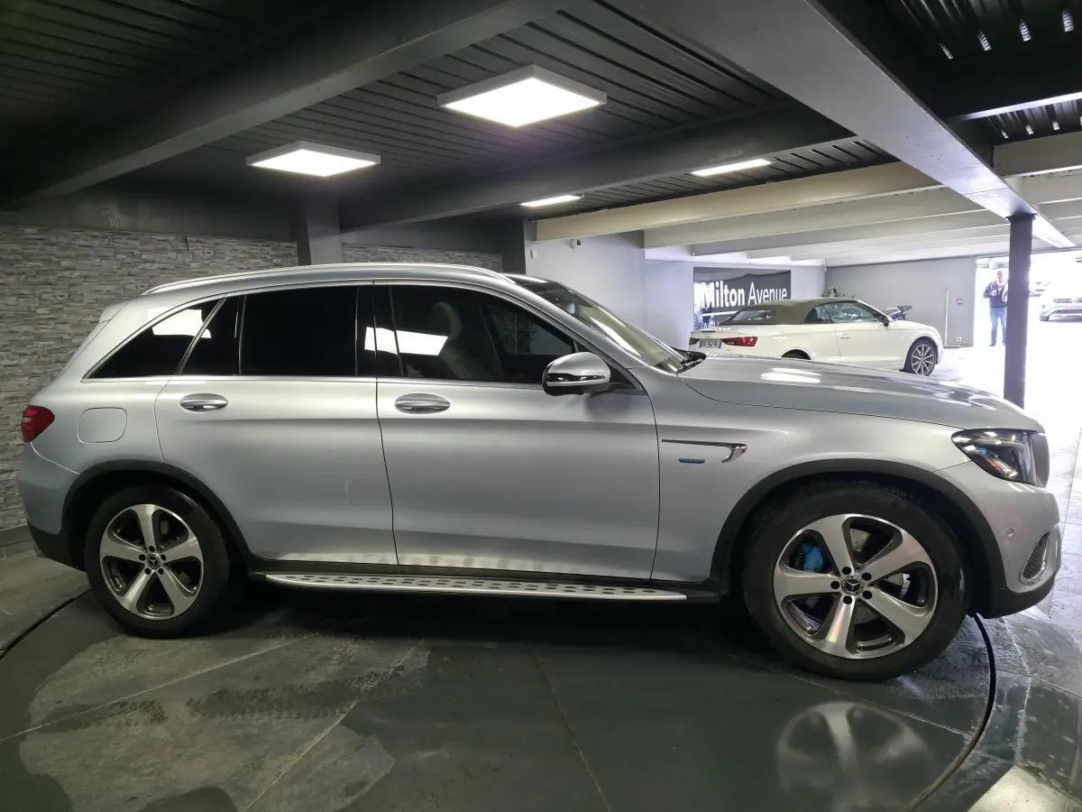 Vue de profil côté gauche d'un Mercedes GLC 350 e gris métallisé avec jantes alliage et marchepieds en acier.