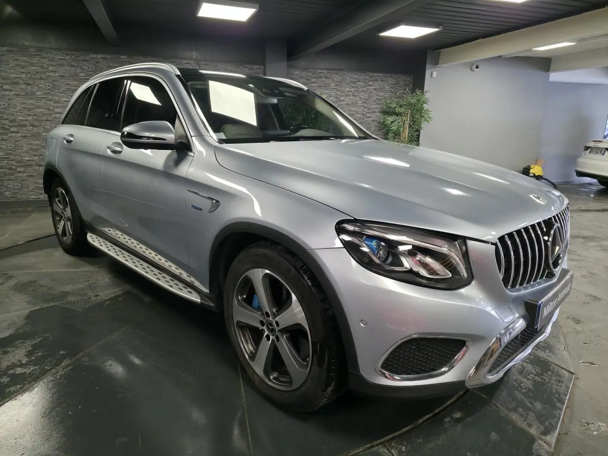 Mercedes GLC 350 e gris métallisé en vue 3/4 avant droit, avec jantes alliage 19 pouces et marchepieds inox.