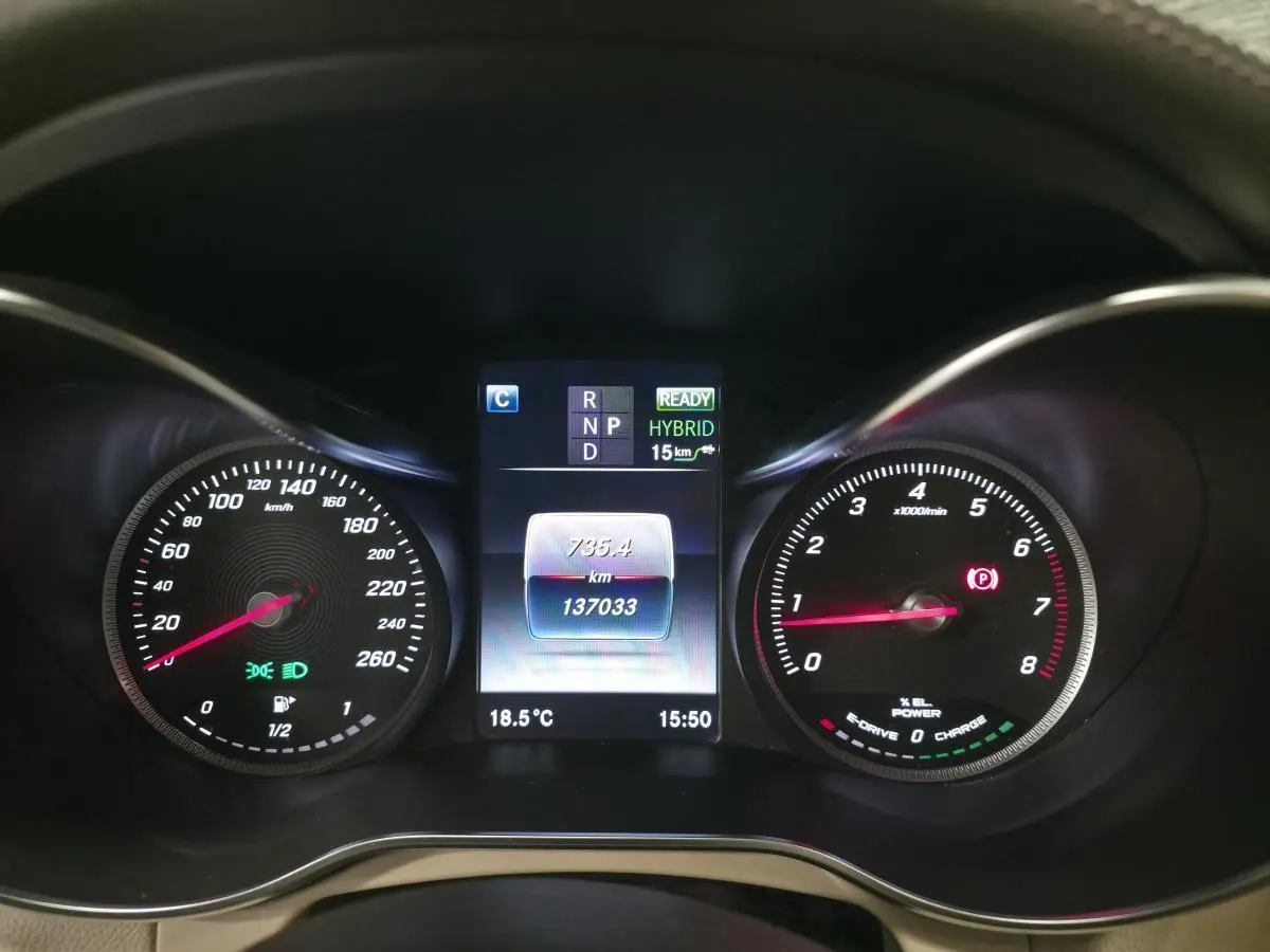 Vue rapprochée du combiné d'instruments numérique du Mercedes GLC 350 e gris, affichant mode hybride et compteur kilométrique.