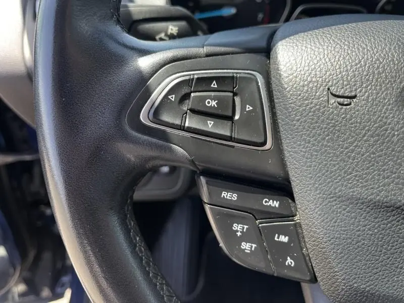 Gros plan sur les commandes au volant à gauche du Ford Kuga 1.5 EcoBoost 2018, cuir noir avec boutons de régulateur de vitesse.