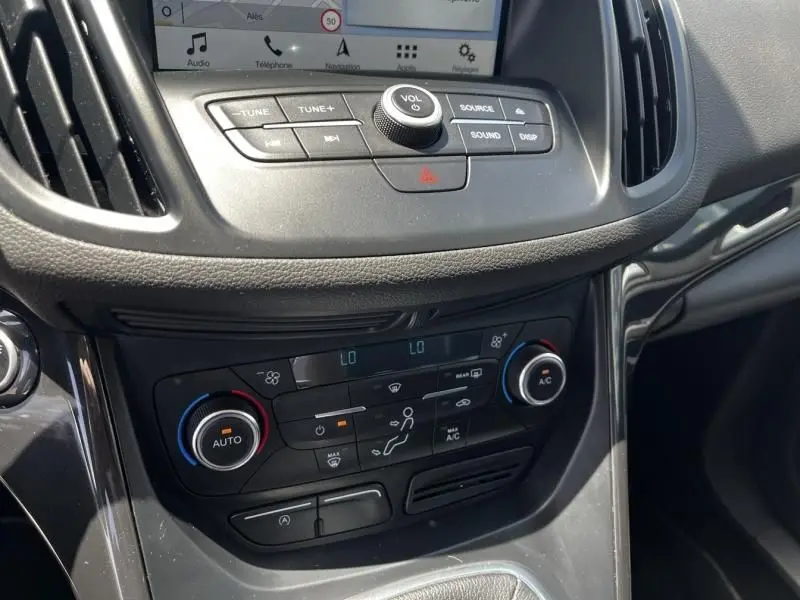 Vue rapprochée de la console centrale du Ford Kuga 2018, montrant les commandes de climatisation et l’écran tactile.