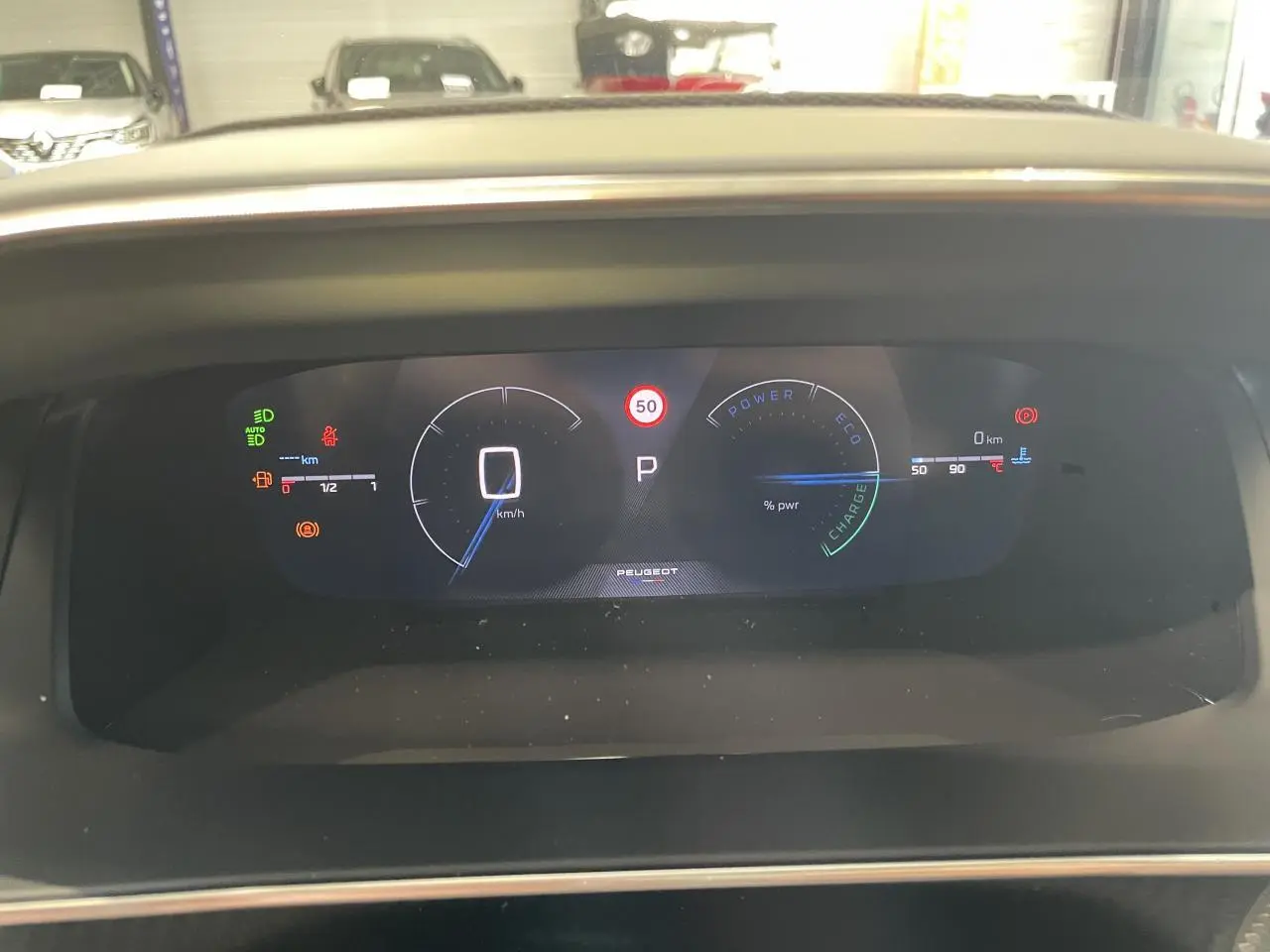 Vue rapprochée du tableau de bord numérique du Peugeot 2008 gris 1.2i Hybrid 2026, affichant la vitesse à 0 km/h.