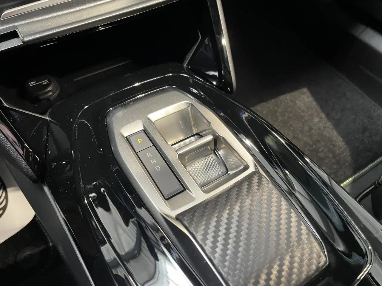 Gros plan sur la console centrale du Peugeot 2008 gris 2026, mettant en valeur la commande de boîte automatique et le décor carbone.