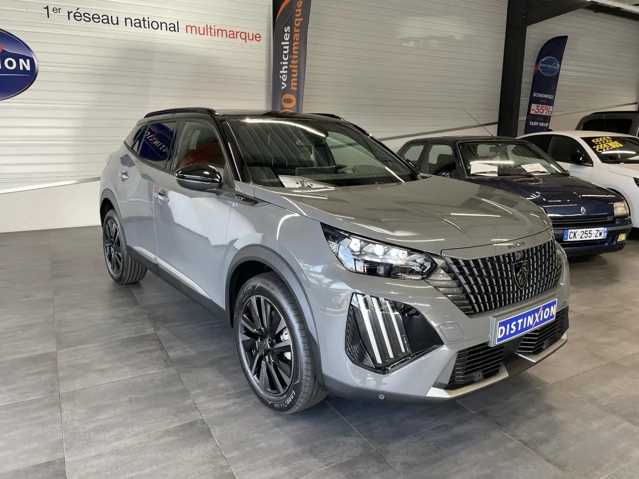 Peugeot 2008 gris 3/4 avant droit en showroom, avec calandre noire et jantes alliage noires distinctives.