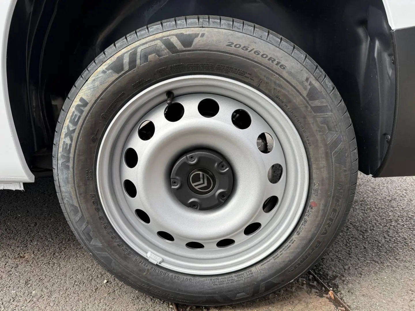 Gros plan sur la roue avant droite en acier gris du Citroën Berlingo Fourgon blanc Icy.
