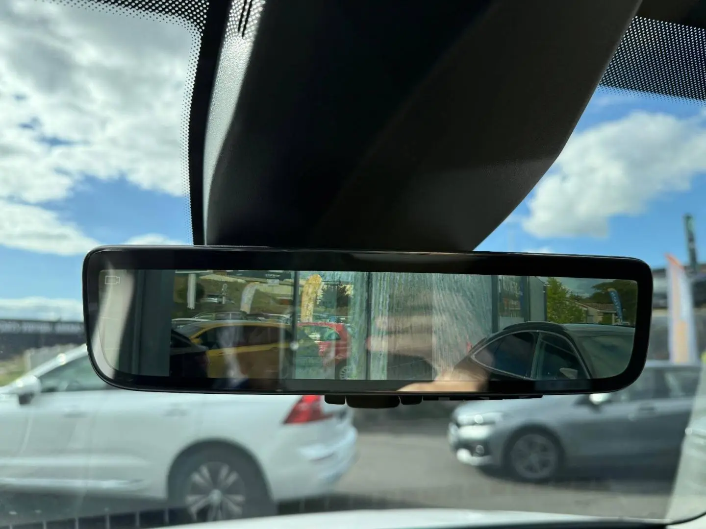 Rétroviseur intérieur affichant une vue arrière sur un Citroën Berlingo Fourgon blanc Icy en stationnement.