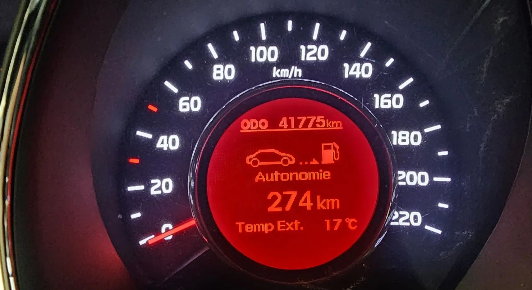 Gros plan sur le compteur de vitesse rouge d'une Kia Rio noire de 2015, affichant 41 775 km et 274 km d'autonomie.