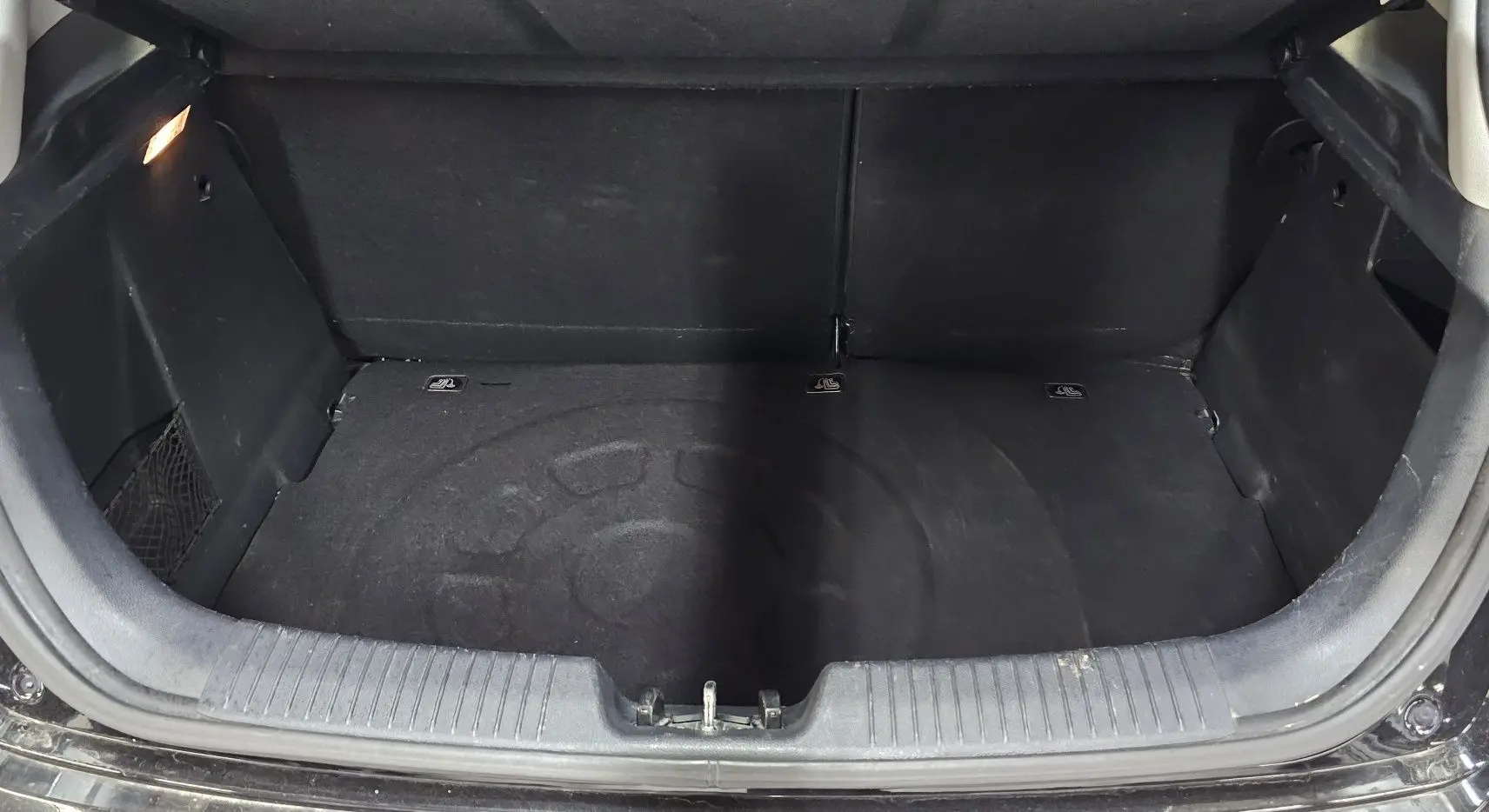 Coffre ouvert d'une KIA RIO III noire de 2015, montrant un espace de rangement vide et propre.